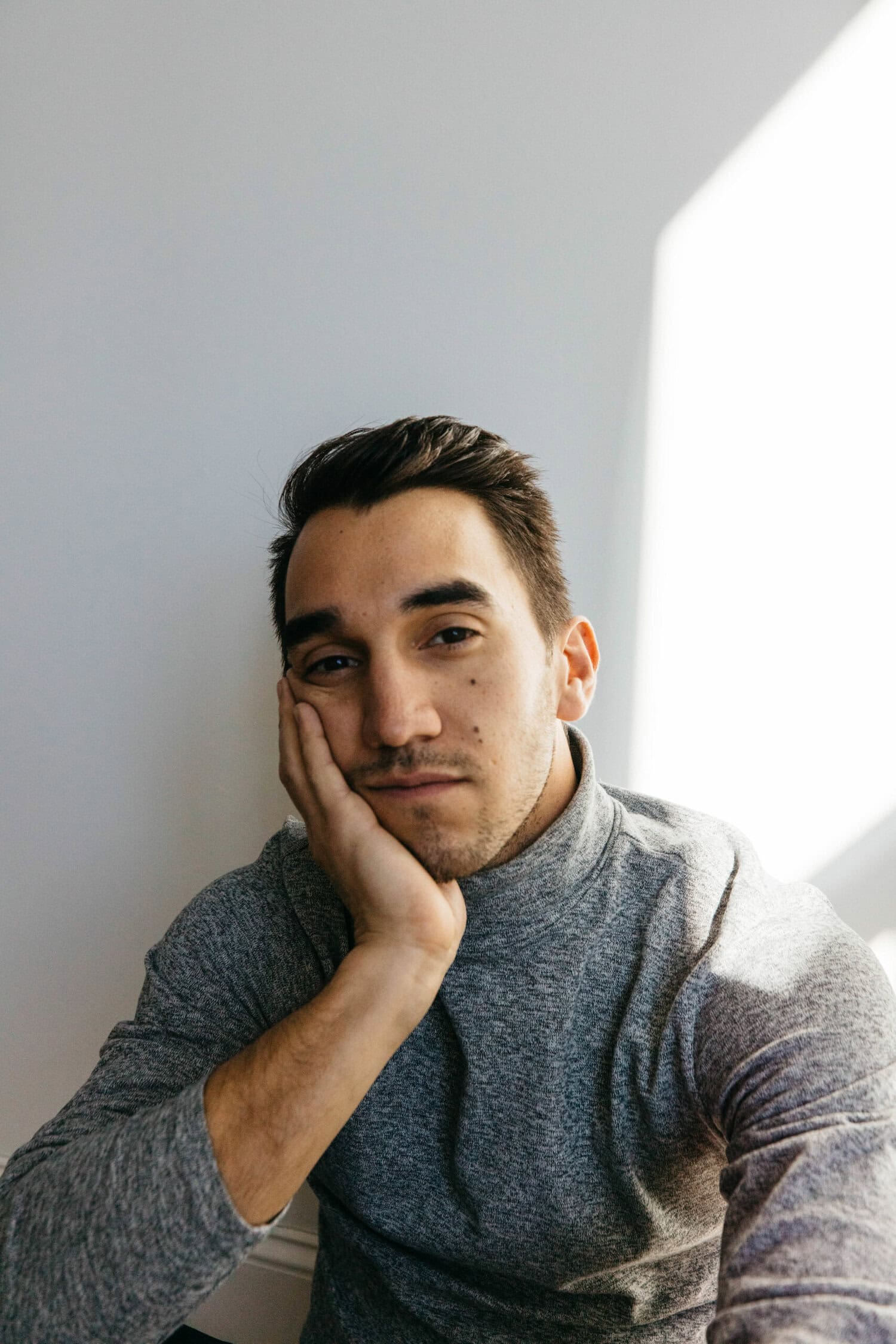 Adam Benavides - Filmmaker, Director, sitting with a grey long sleeved shirt.