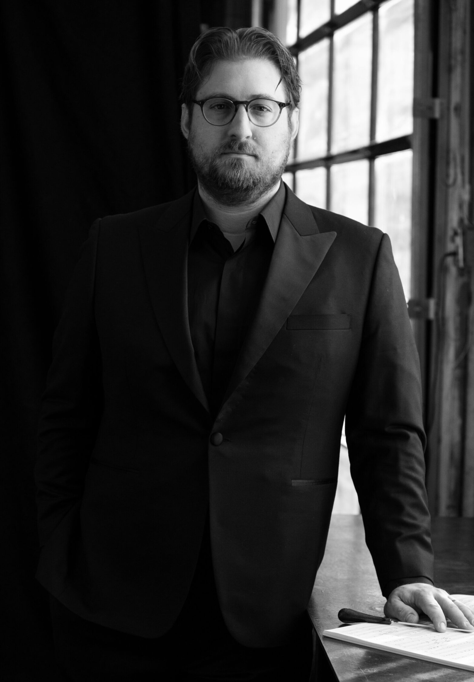 Matthew Kasper, PYSO Artistic Director, standing and wearing a black suit